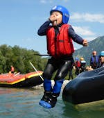 Ein Kind springt bei einer Raftingtour auf der Iller im Allgäu mit Naturgeister Allgäu vom Raftingboot in den Fluss.