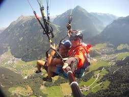 Een klant en zijn piloot lachen in de camera tijdens het tandem paragliden in het Zillertal in Mayrhofen met Fly 2095.