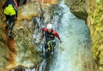 A participant of the Canyoning for Discoverers in the Taxaklamm with Adventure Club Kaiserwinkl is sliding down a waterfall in the canyon.
