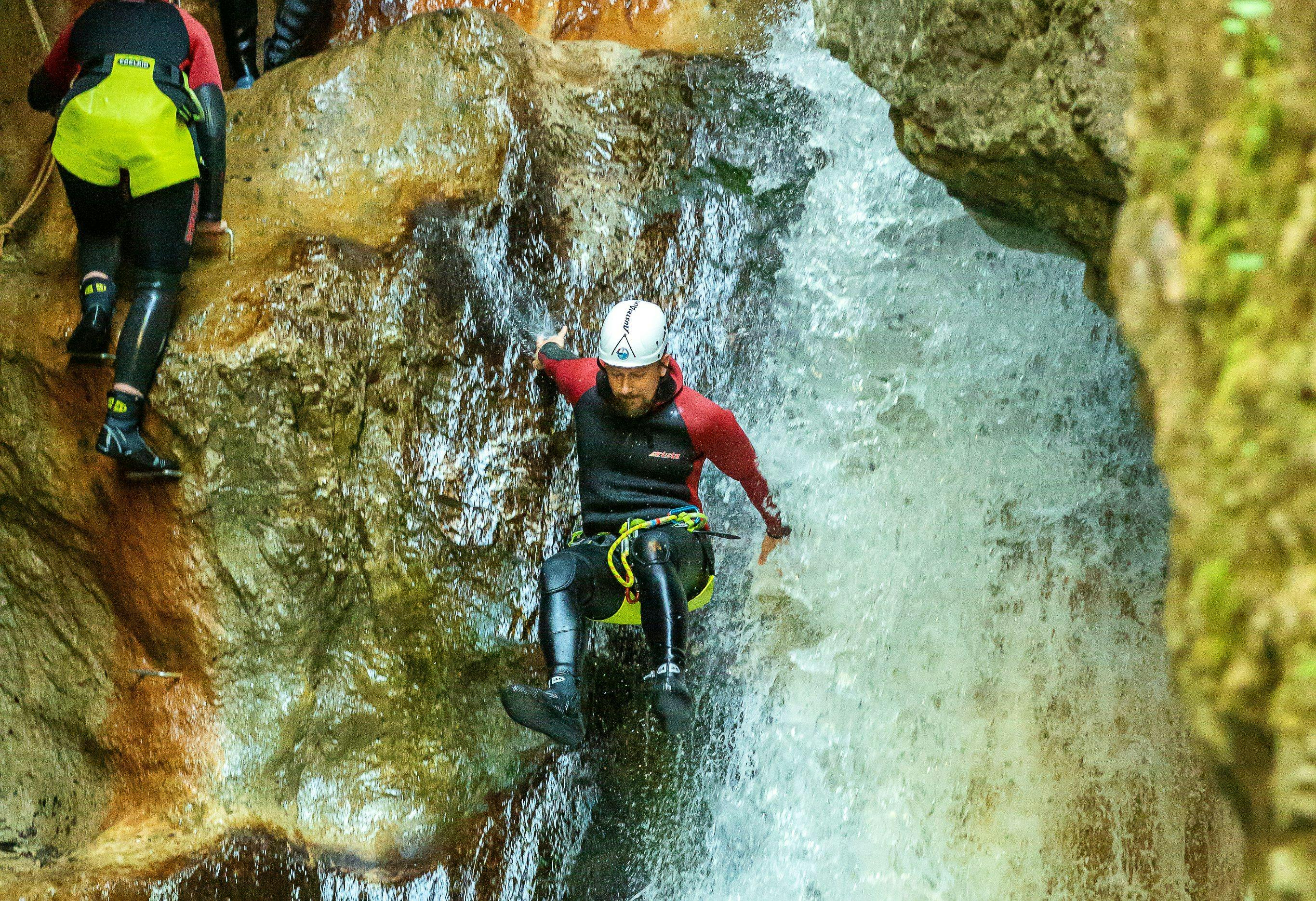 Canyoning in the Kaiserwinkl Region near Kössen A participant of the Canyoning for Discoverers in the Taxaklamm with Adventure Club Kaiserwinkl is sliding down a waterfall in the canyon.