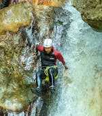 Ein Teilnehmer des Canyoning für Entdecker in der Taxaklamm mit Adventure Club Kaiserwinkl rutscht über einen Wasserfall in der Schlucht.