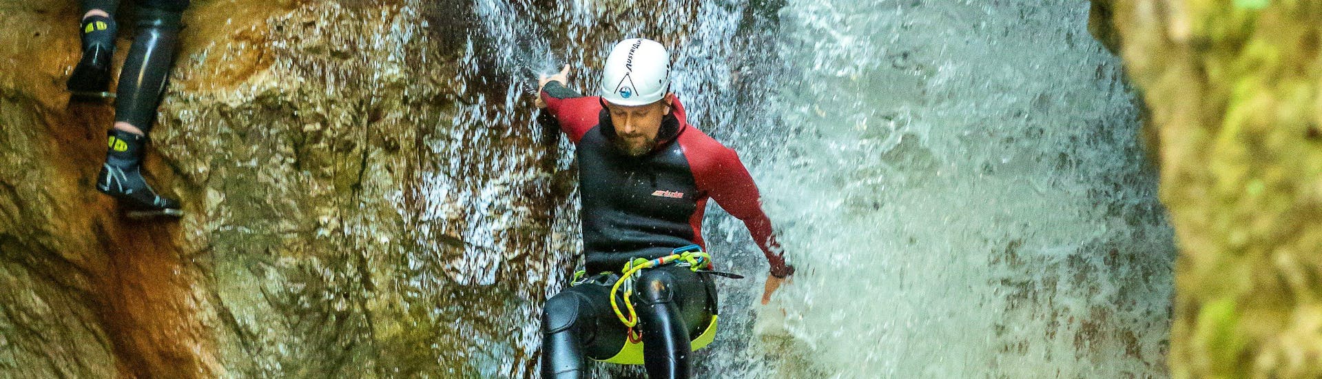 Ein Teilnehmer des Canyoning für Entdecker in der Taxaklamm mit Adventure Club Kaiserwinkl rutscht über einen Wasserfall in der Schlucht.