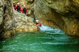 A woman sliding down into a natural pool on her Outdoor-Combi Rafting & Canyoning with the local guides from Adventure Club Kaiserwinkl. 