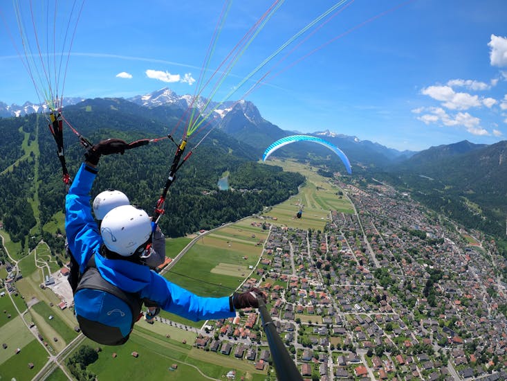 Immagine della guida con un partecipante che vola in aria e si gode il panorama durante il volo in parapendio tandem a Garmisch-Partenkirchen con Aerotaxi Garmisch-Partenkirchen.