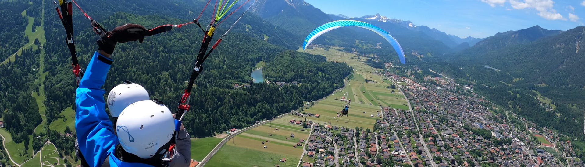 Picture of guide with a participant, flying in the air and enjoying the view during the Tandem Paragliding in Garmisch-Partenkirchen with Aerotaxi Garmisch-Partenkirchen.