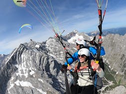 Guide with participant over the mountains during tandem paragliding in Garmisch-Partenkirchen with Aerotaxi Garmisch-Partenkirchen.