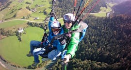 A child and instructor flying through the air during Tandem Paragliding from Unterberghorn for Kids (up to 14 y.) Airtaxi Kössen.