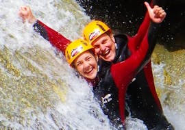 A man and a woman standing next to a waterfall and smiling into the camera during Classic Canyoning in Zemmschlucht from Mayrhofen with Actionclub Zillertal.