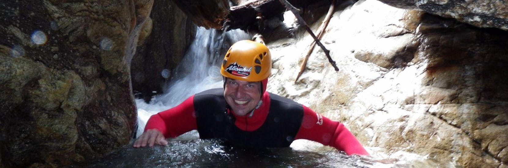 A man smiling into the camera whle slowly sliding down a natural slide during the XL Canyoning in Zemmschlucht near Mayrhofen with Actionclub Zillertal.