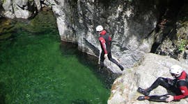 A man is jumping in an emerald pool during his Classic Canyoning in Canyon Aéro Besorgues with Geo Ardèche Canyon.