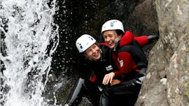 Deux amies s'amusent sous une cascade lors de leur descente de Canyoning dans le canyon de la Haute Besorgues pour Tous avec Géo Canyon Ardèche.