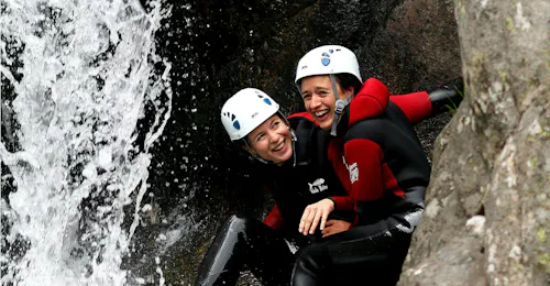 Ontdek Canyoning in de Haute Besorgues Canyon in de Ardèche Twee vrienden vermaken zich onder een waterval tijdens hun Canyoning in Canyon de la Haute Besorgues voor iedereen met Geo Ardèche Canyon.