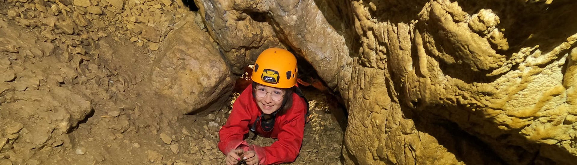 Alguien está progresando en una cueva durante su actividad de espeleología "discovery" en Les Deux Avens, con Geo Ardèche Canyon.
