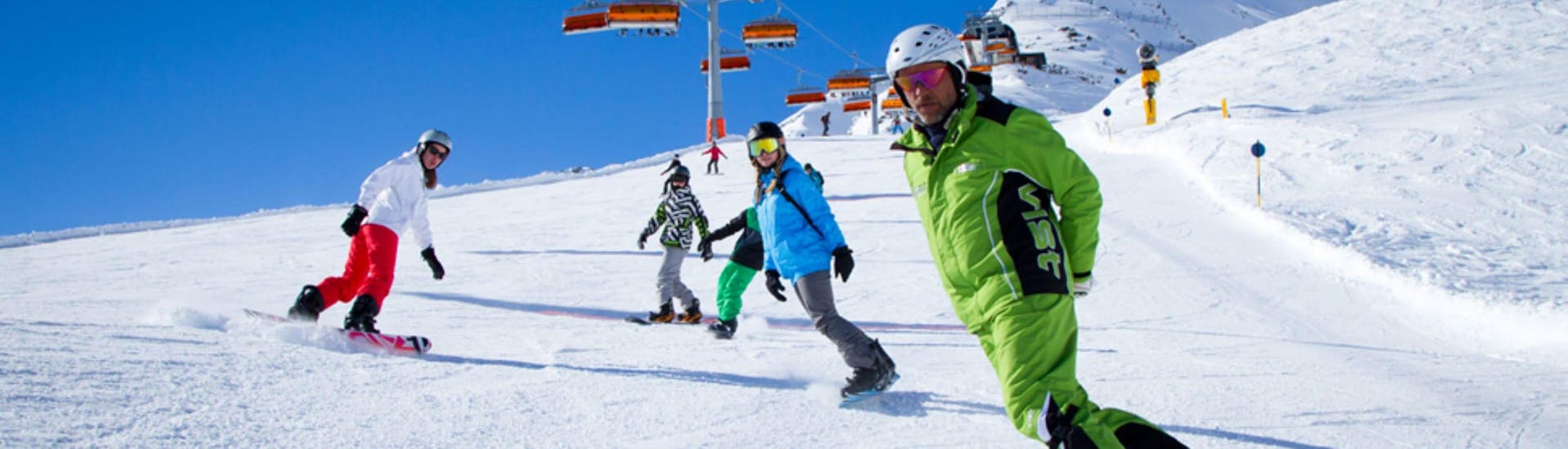 A group of people is learning to snowboard during their Snowboarding Lessons for Kids & Adults - All Levels with the ski school Ski- und Bikeschule Ötztal Sölden.