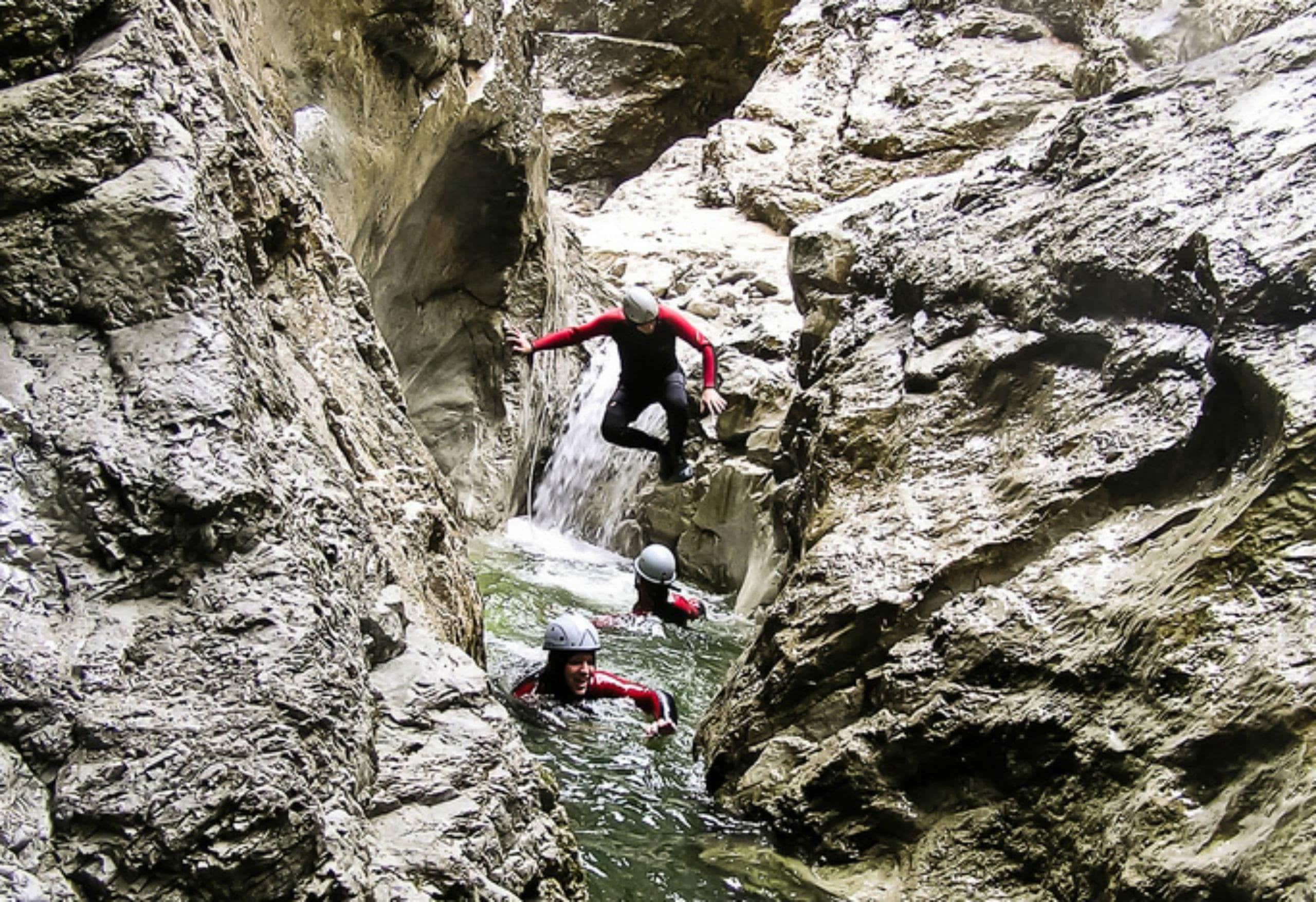 Participants of the canyoning trip Classic in the Nyon Canyon with 7 Aventures are jumping into the water.