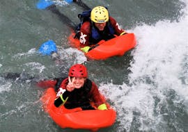 Two participants of the Hydrospeed Easy organized by X Raft Val di Sole are smiling at the camera while floating on the river noce.