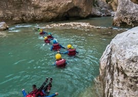Participants of the river trekking tour Couloir Samson with Yeti Rafting are floating in the emerald waters of the Gorges du Verdon.