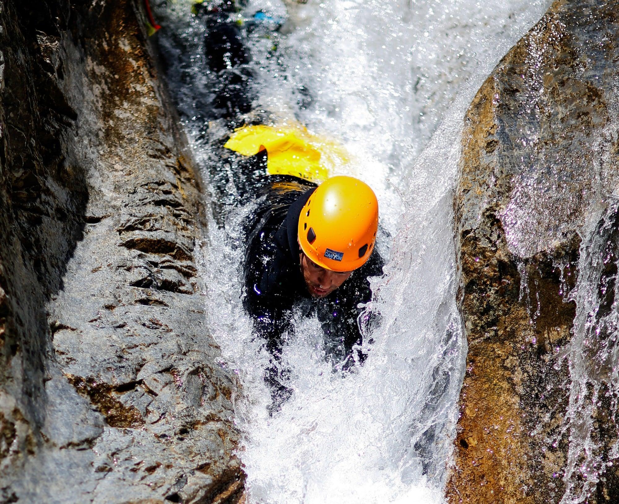 A man is sliding down a natural slide head first during his Canyoning in Canyon des Acles - Dynamic tour with SerreChe Canyon.
