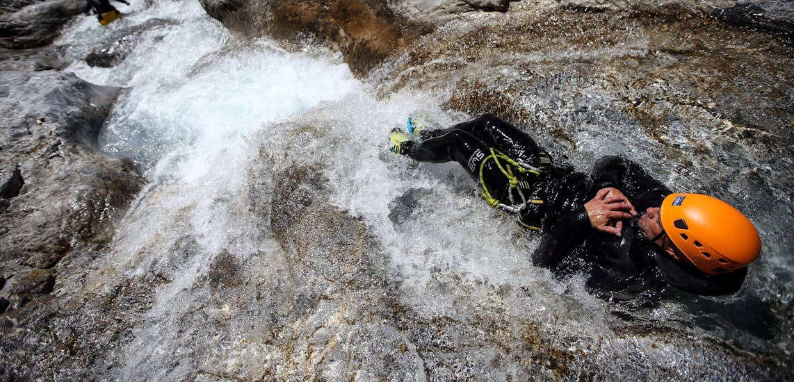 A man is sliding down a natural slide during his Canyoning in Canyon du Foresto - Italian Adventure tour with SerreChe Canyon.