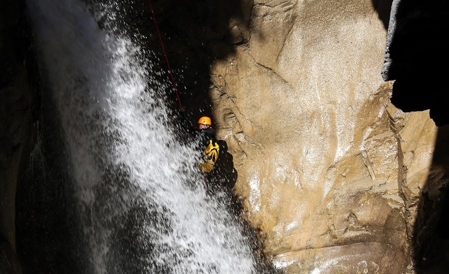 A man is abseiling down a waterfall during his Canyoning in Canyon des Oules de Freissinières - Expert tour with SerreChe Canyon.
