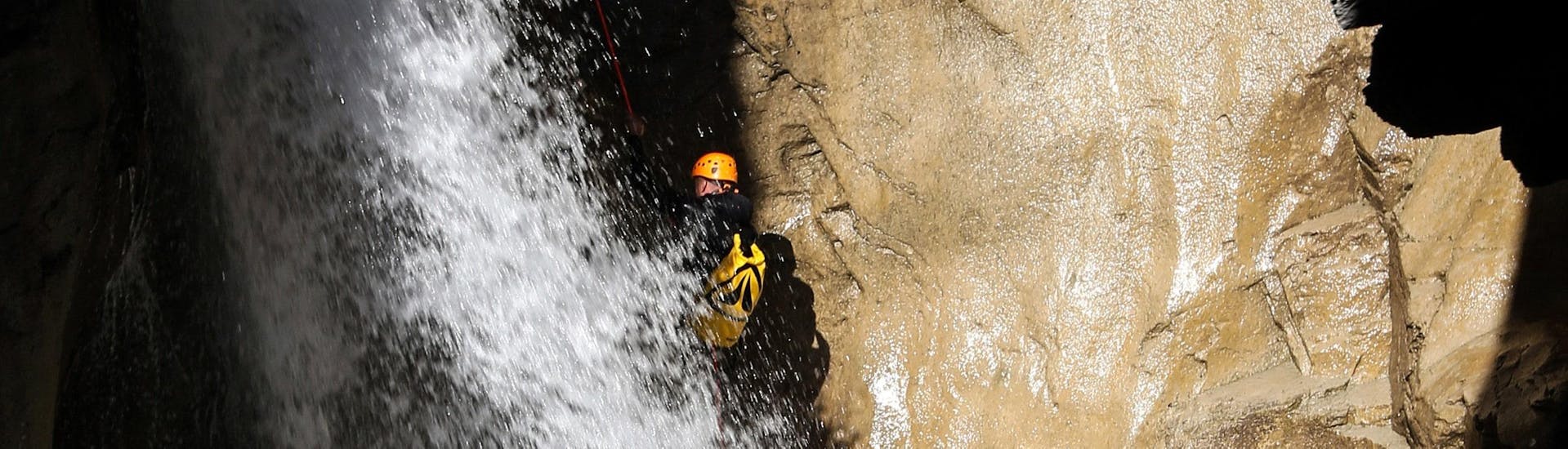 A man is abseiling down a waterfall during his Canyoning in Canyon des Oules de Freissinières - Expert tour with SerreChe Canyon.