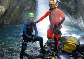 Two men are posing for a picture in front of a waterfall during their Canyoning in Canyon des Oules de Freissinières - Expert tour with SerreChe Canyon.