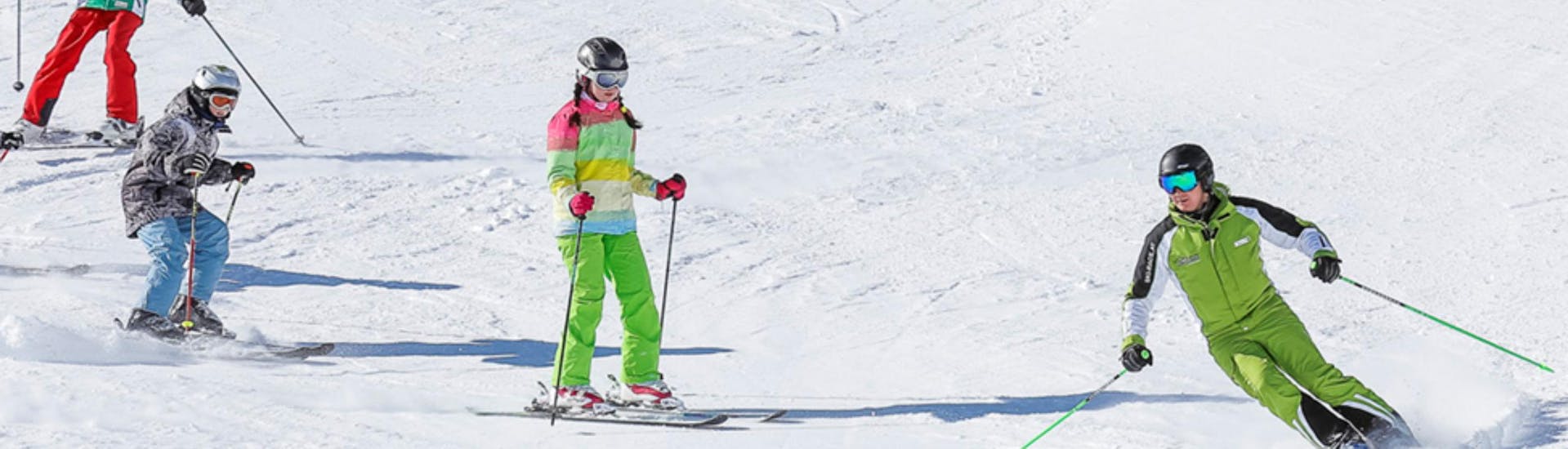 Eine Gruppe Kinder folgt bei der Aktivität Kinder Skikurs (3-14 Jahre) - Alle Levels ihrem Skilehrer der Ski- und Bikeschule Ötztal Sölden während sie die Piste hinunterfahren.