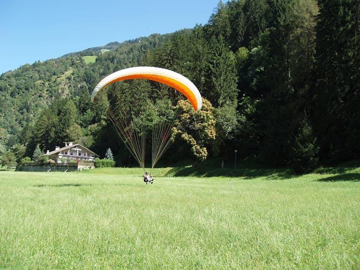 A participant is swiftly landing on the ground after the Tandem Paragliding at Punta Cervina - Thermal Flight with FlyHirzer Saltusio.