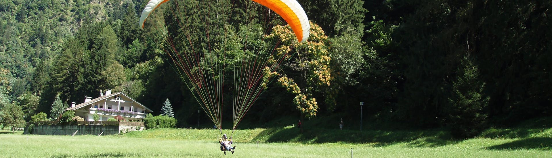 A participant is swiftly landing on the ground after the Tandem Paragliding at Punta Cervina - Thermal Flight with FlyHirzer Saltusio.