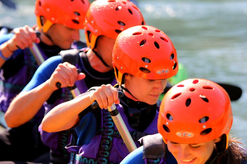 A group of people wearing orange helmets row during Rafting on the Adda - Full Fun of Rafting Lombardia.