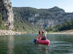 During the descent of the river section "Heart of the Canyon - 24km" in Ardèche, a couple is admiring the wonderful landscapes by paddling a canoe rented at Aigue Vive.