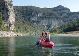 During the descent of the river section "Heart of the Canyon - 24km" in Ardèche, a couple is admiring the wonderful landscapes by paddling a canoe rented at Aigue Vive.