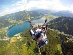 Our paragliding instructor with a costumer flying over the lake while Tandem Paragliding in Zell am See from Schmittenhöhe with Paragliding Zell am See.