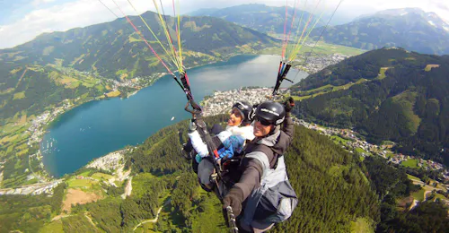 Parapendio in tandem a Zell am See dallo Schmittenhöhe con Paragliding Zell am See. Il nostro istruttore di parapendio con un cliente che sorvola il lago mentre fa parapendio in tandem a Zell am See da Schmittenhöhe con Paragliding Zell am See.