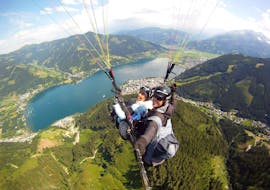 Notre instructeur de parapente avec un client survolant le lac pendant le parapente en tandem à Zell am See depuis Schmittenhöhe avec Paragliding Zell am See.