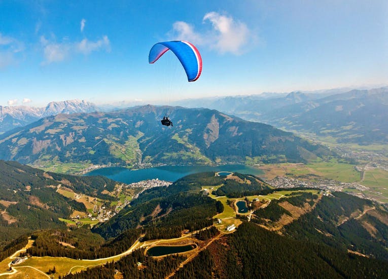Il pilota e un cliente si godono il panorama e il lago durante il parapendio tandem a Zell am See da Schmittenhöhe con Paragliding Zell am See.
