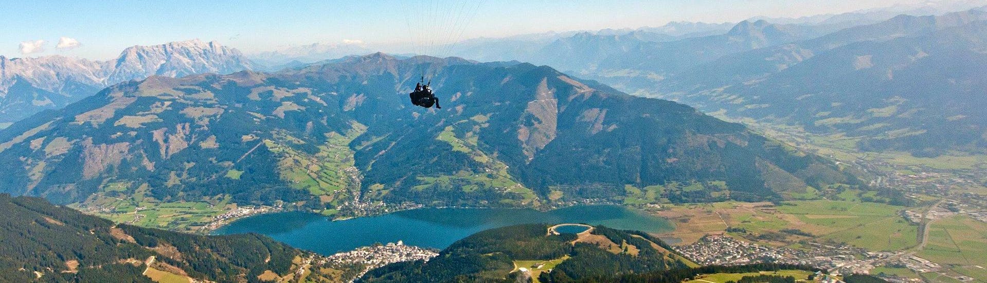 De piloot en de gast genieten van het uitzicht op het meer tijdens het tandem paragliding in Zell am See vanaf Schmittenhöhe mit Paragliding Zell am See.