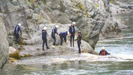 View of a group of people on the rocky shore of the river Sesia during the Canyoning in the Sesia Gorges with Centro Canoa e Rafting Monrosa.