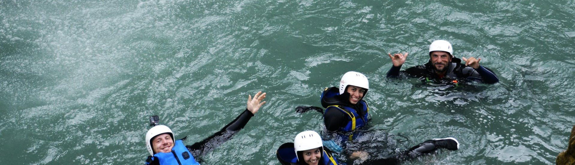 Un gruppo di amici e una guida si divertono galleggiando nell'acqua con l'attrezzatura da canyoning durante il Canyoning nel fiume Sorba con Centro Canoa e Rafting Monrosa.