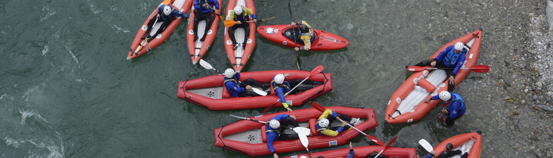 Un gruppo di mini-raft visto dall'alto su un fiume vivace durante il Mini-Raft sul Sesia con il Centro Canoa e Rafting Monrosa.
