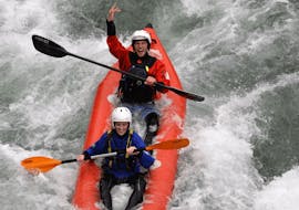 Two people on a mini-raft descend a rapid while laughing during the Mini-Raft on the Sesia with Centro Canoa e Rafting Monrosa.