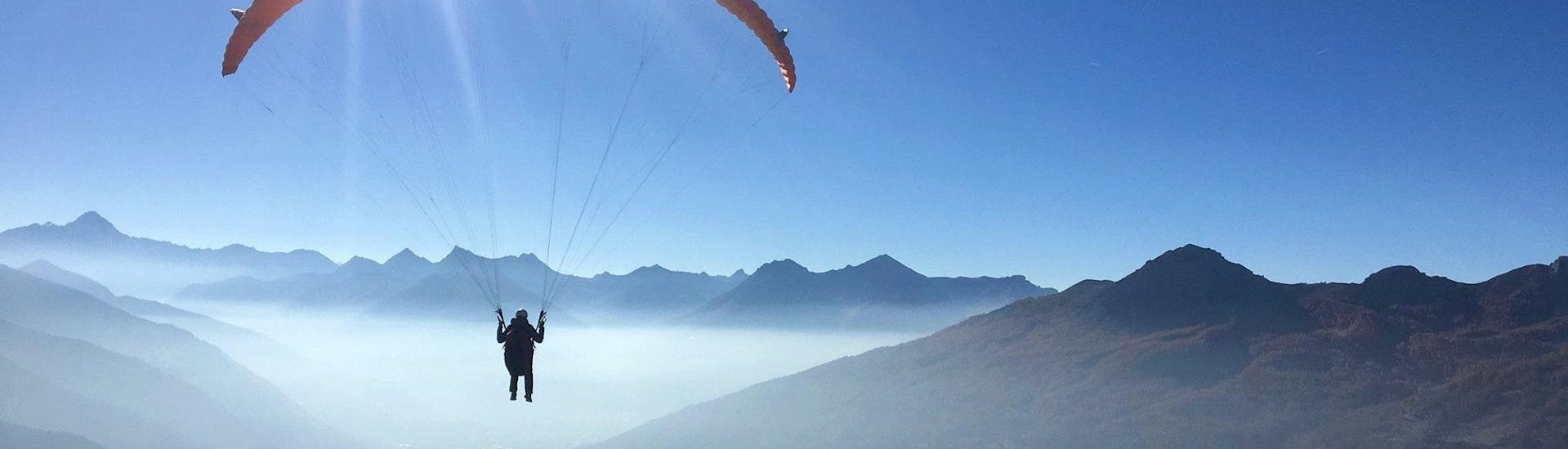 A paragliding pilot from Emotion'Air is doing a Tandem Paragliding Prestige Flight from the Col du Galibier.