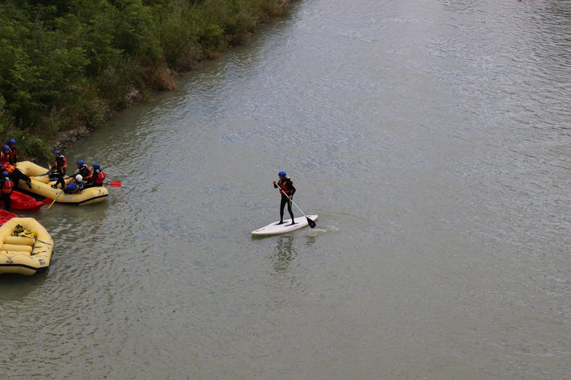 Un partecipante si avvicina alla riva del fiume durante la SUP River Experience sul fiume Adda con Indomita Valtellina.