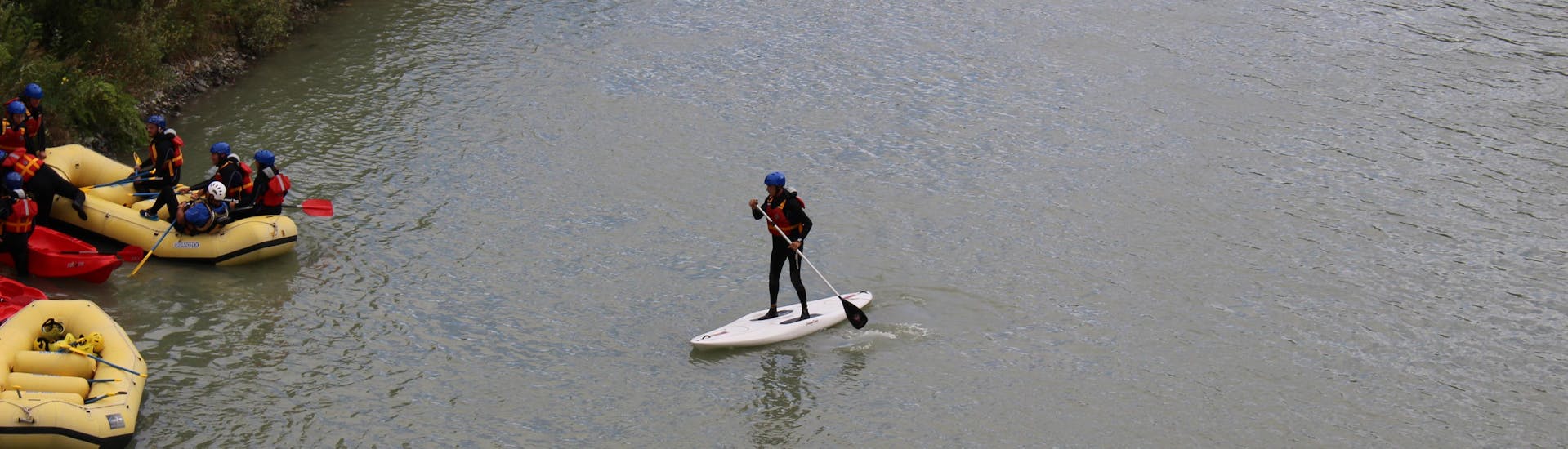 A participant is approaching the bank of the river during the SUP River Experience on the Adda River with Indomita Valtellina River.