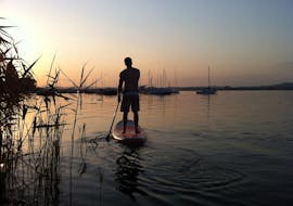 Een persoon geniet van de zonsondergang terwijl Stand-Up-Paddleboarden op de Bodensee met MB Events & Adventures Allgäu & Bodensee.