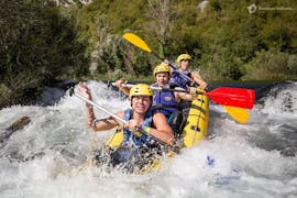Drie vrienden hebben plezier terwijl ze door een stroomversnelling peddelen tijdens het raften op de Cetina rivier met Adventure Dalmatia.