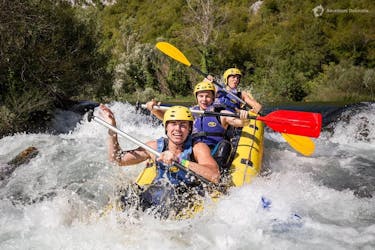 Drie vrienden hebben plezier terwijl ze door een stroomversnelling peddelen tijdens het raften op de Cetina rivier met Adventure Dalmatia.