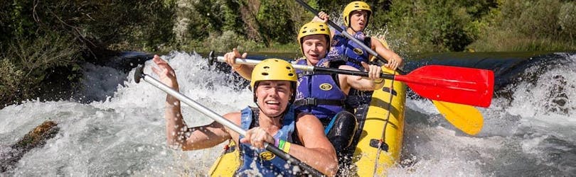 Trois amis s'amusent en pagayant à travers un rapide pendant le Rafting sur la rivière Cetina avec Adventure Dalmatia.