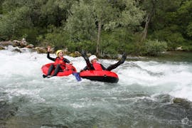 Zwei Teilnehmer des von Adventure Dalmatia organisierten Rivertubing auf der Cetina mit City-Transfer ab Split amüsieren sich, während sie auf ihren Tubes durch spritzige Stromschnellen treiben.