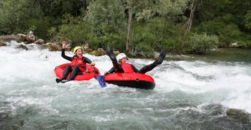 Tubing sur la rivière Cetina avec transfert depuis Split avec Adventure Dalmatia Deux participants au Tubing sur la rivière Cetina avec transfert depuis la ville de Split organisé par Adventure Dalmatia s'amusent en traversant des rapides sur leurs bouées.